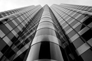 Low angle black and white view of a modern skyscraper in San Francisco, highlighting glass reflections.