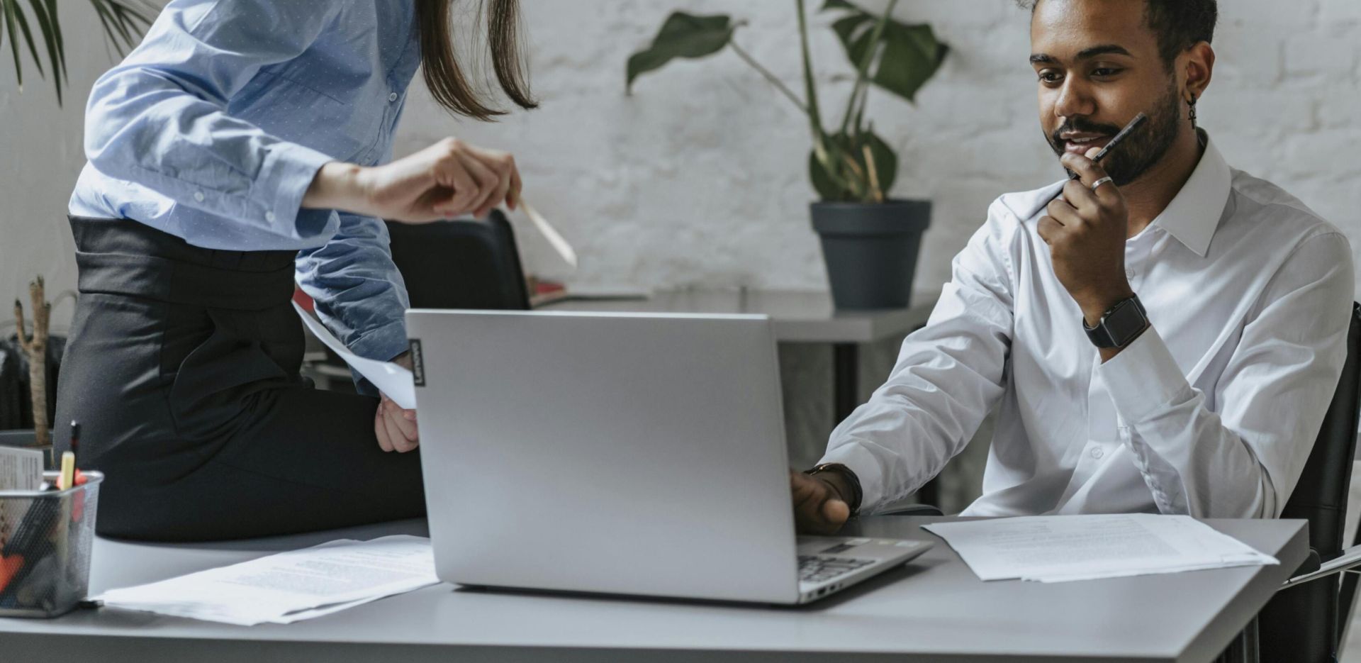 A group of professionals collaborating in a modern office setting, engaging with technology and teamwork.